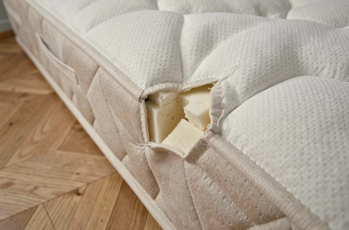 Gros plan sur les dommages structurels d'un matelas plié montrant une déformation des couches internes